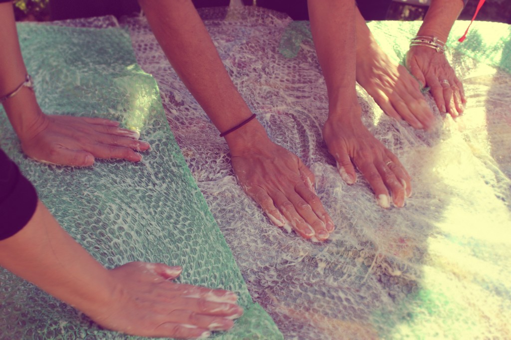 130130 many hands tapping on bubble-wrapped wet-felted blanket to felt the wool