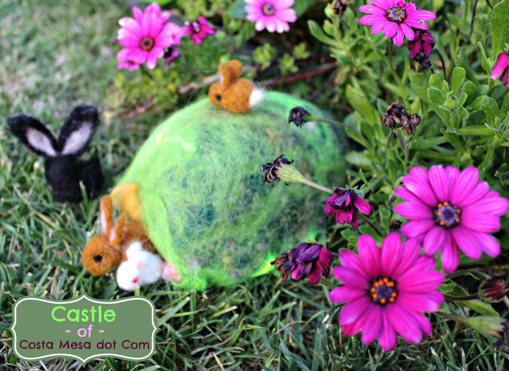 130323 felted bunnies in a burrow on a green spring hill. logo