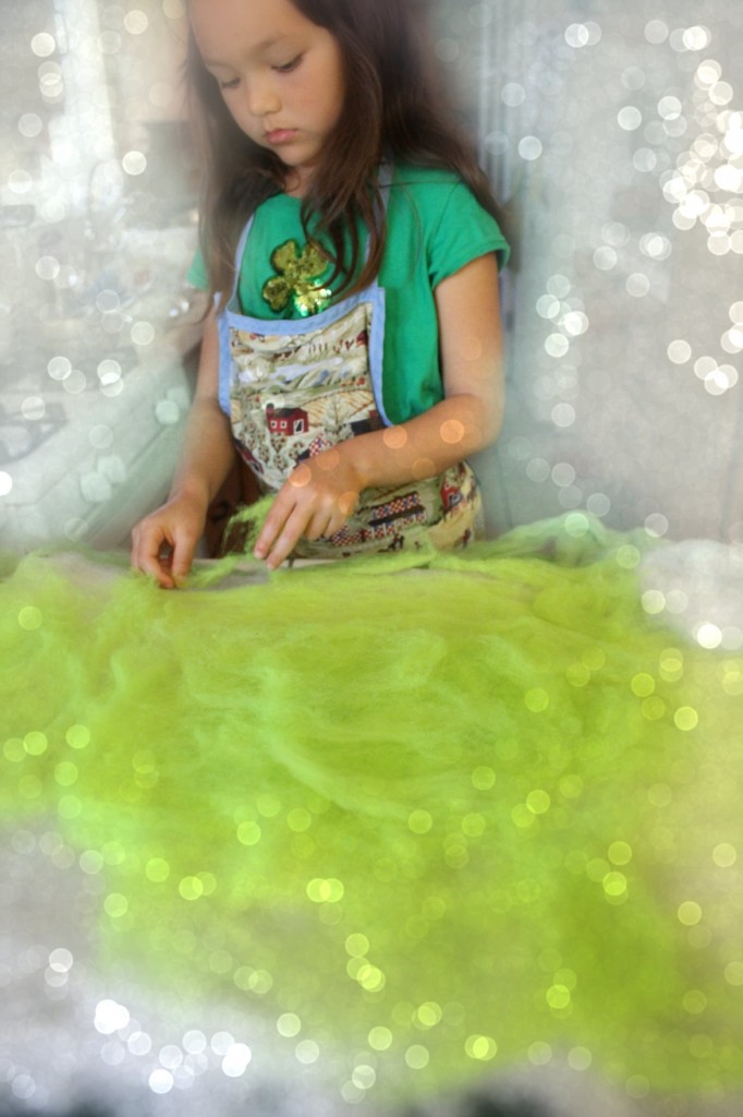 130405 Nunu adding thin, flat layers of chartreuse wool roving to wet-felted playscape project