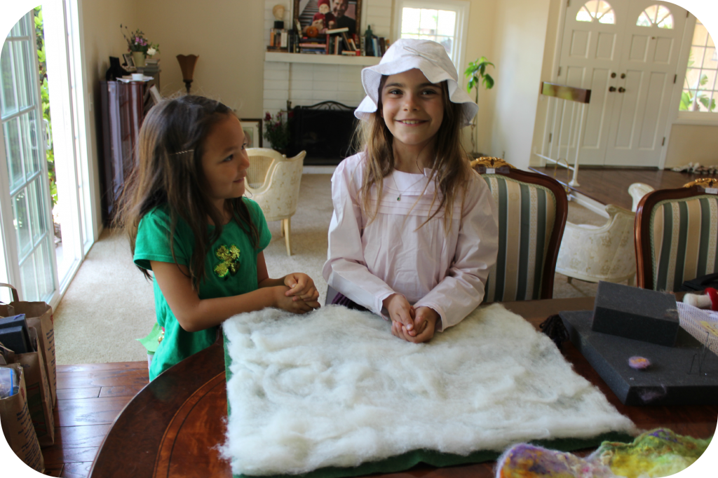 130404 Nunu and Anicka layering flat, thin layers of white batting to make wet-felted Waldorf playscape blanket mat