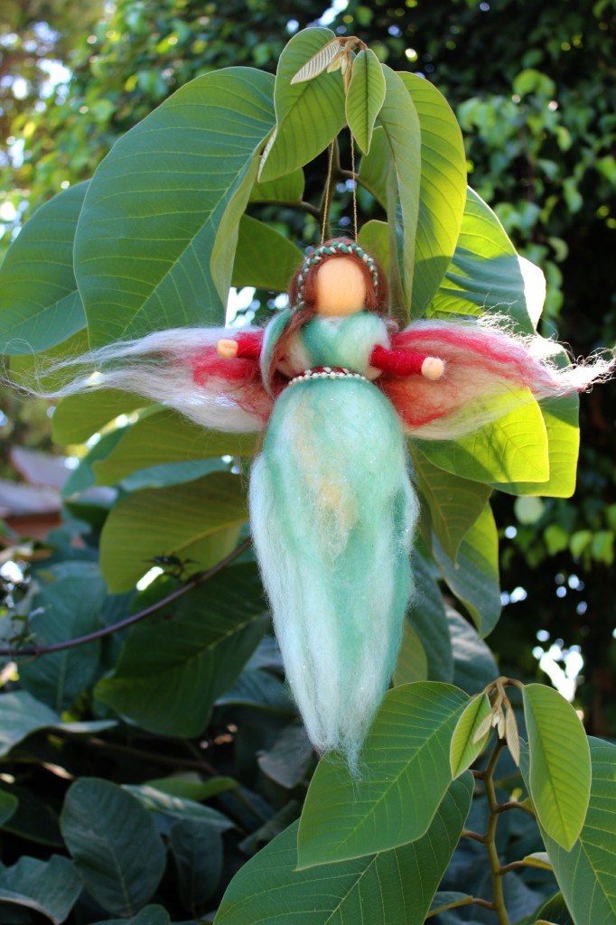 130924 Alena and Anicka's green and red handmade pulled wool roving angel fairy hanging in the cherimoya tree.