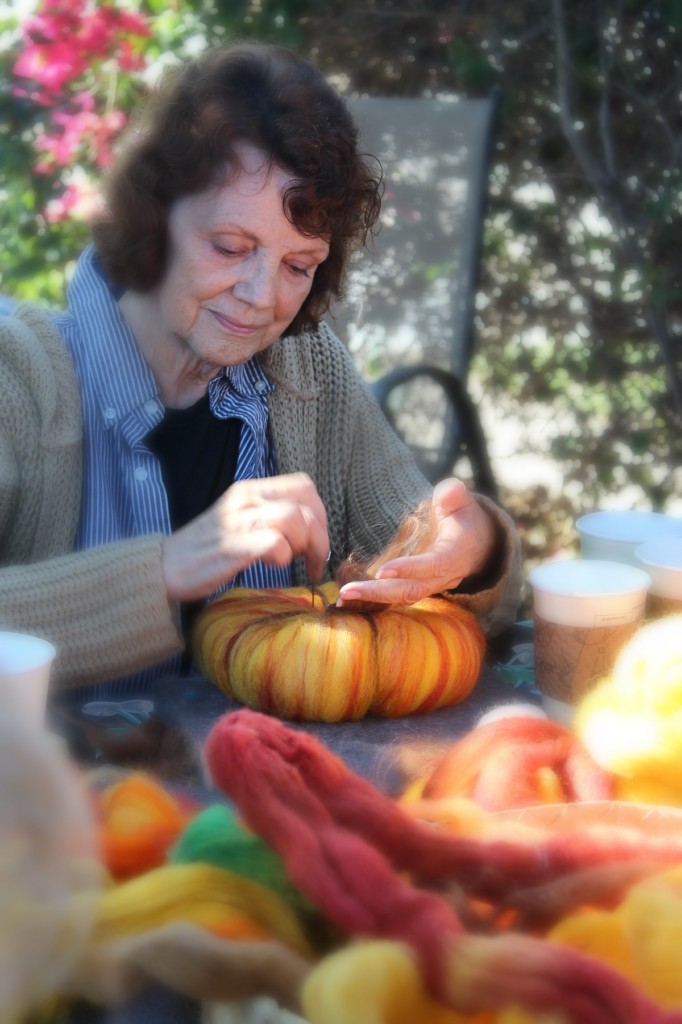 131015 Sharon needle-felting dark strips of wool top roving to create segment on needle-felted pumpkin.