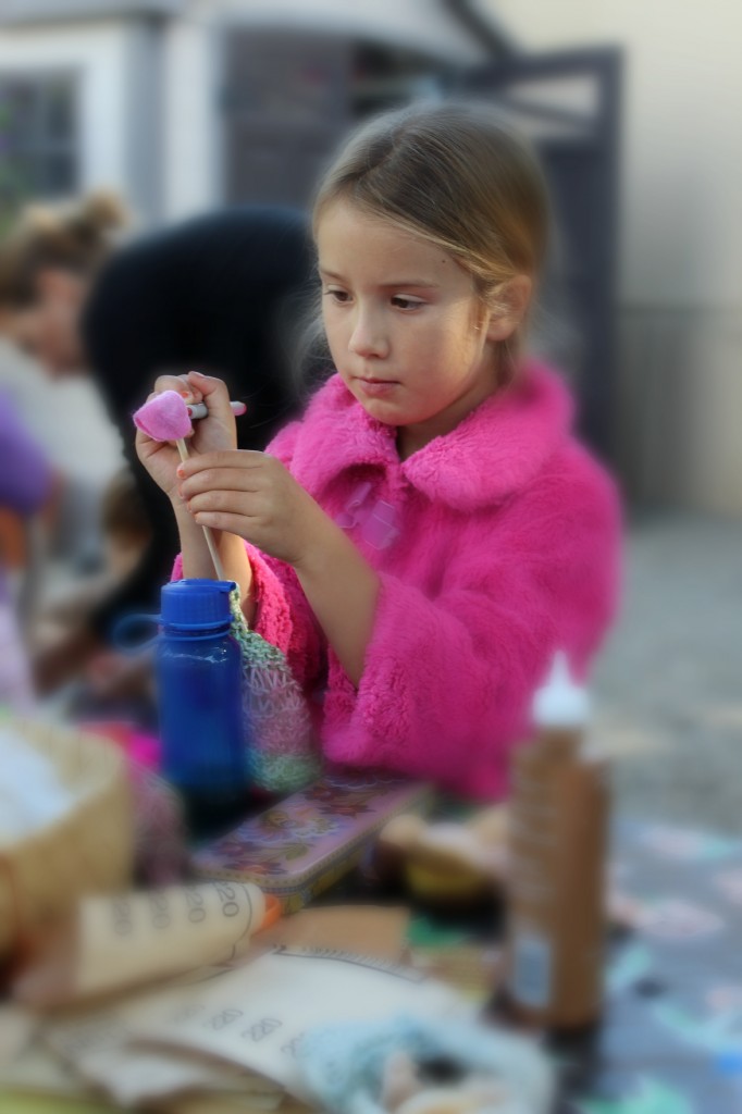 131029 Mia concentrating while drawing a face on her wooden handmade knitting needle doll