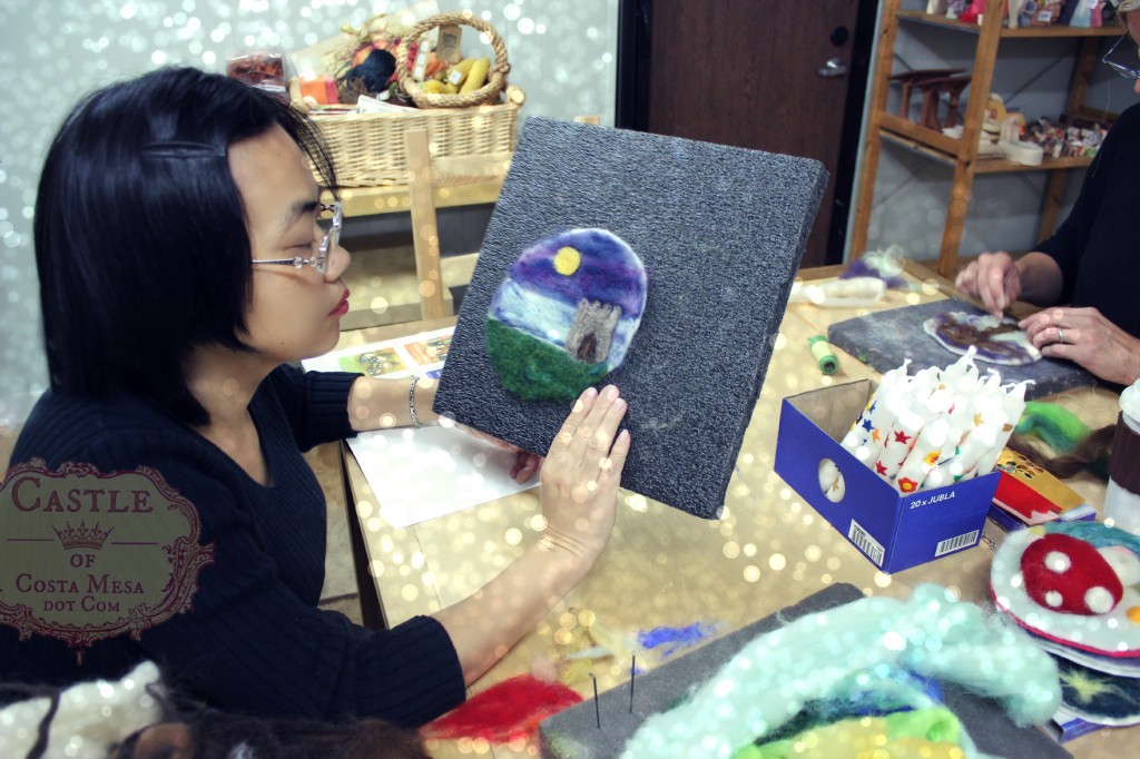 131203 Josephine composing her wool needle-felted picture of a castle in the moonlight on prefelt disc