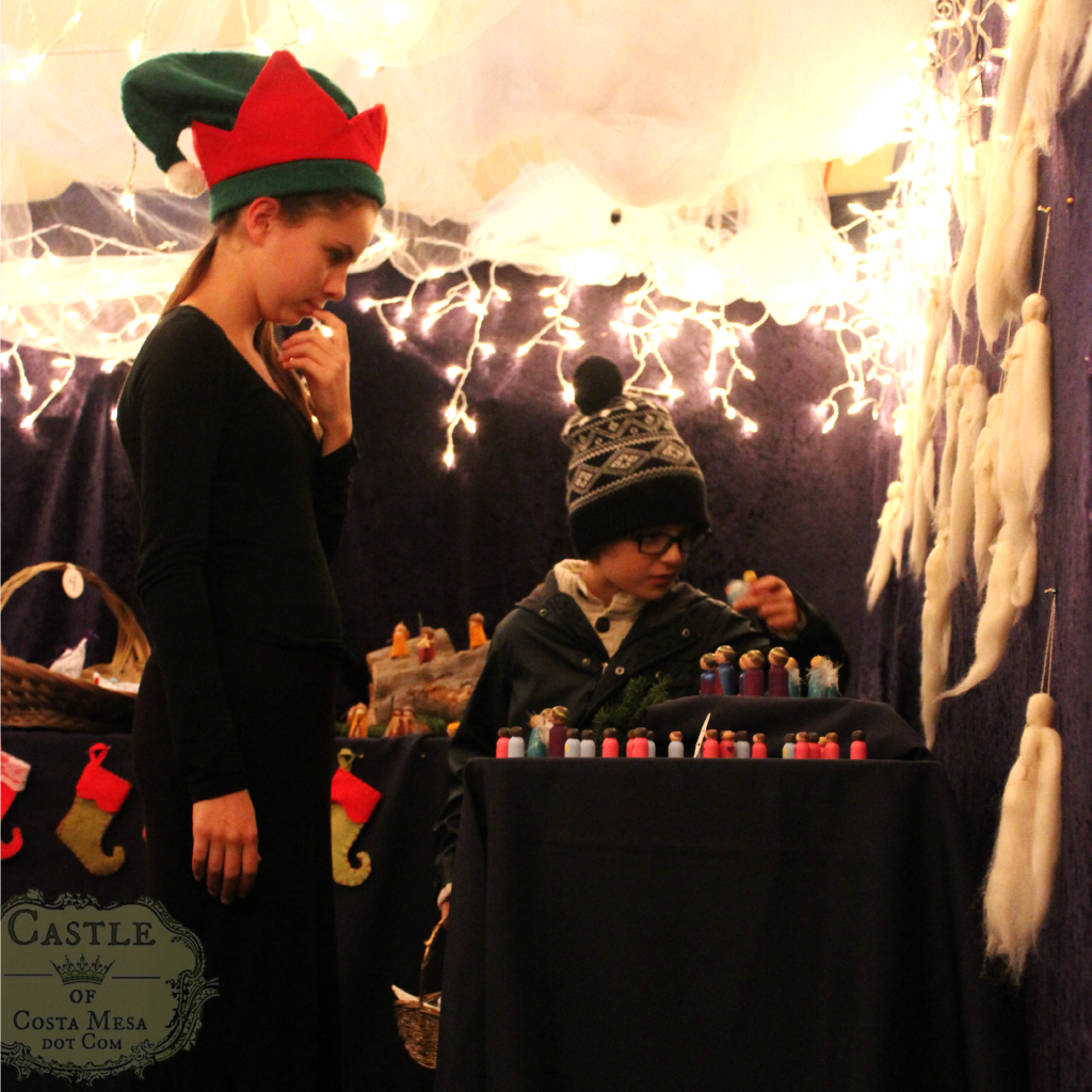 131209 Little boy examining painted wooden peg doll with elf looking on