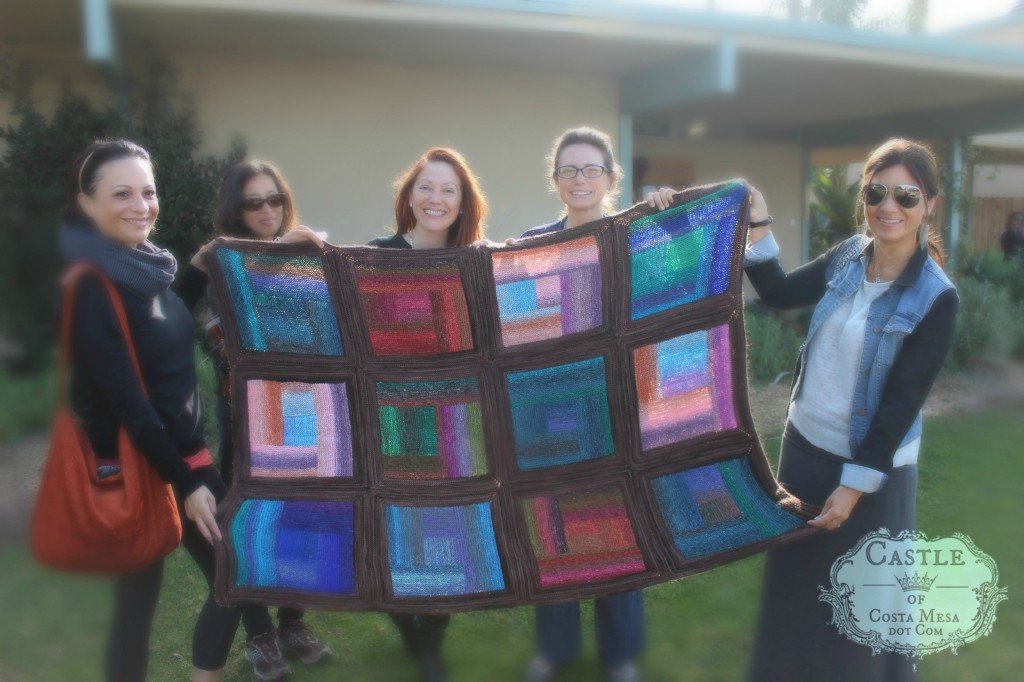 140305 5 women holding up Kim et all community knitted afghan blanket. With logo